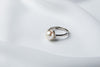 A silver pearl ring on a white cloth background