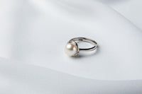A silver pearl ring on a white cloth background