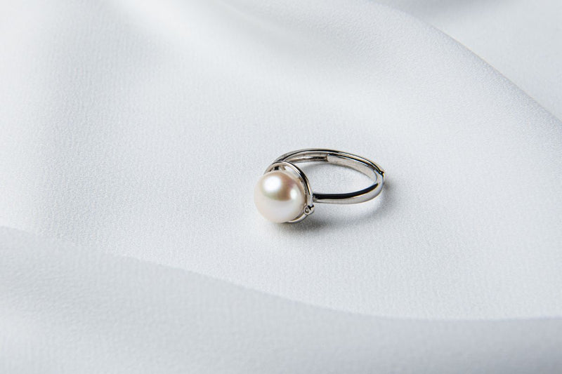 A silver pearl ring on a white cloth background