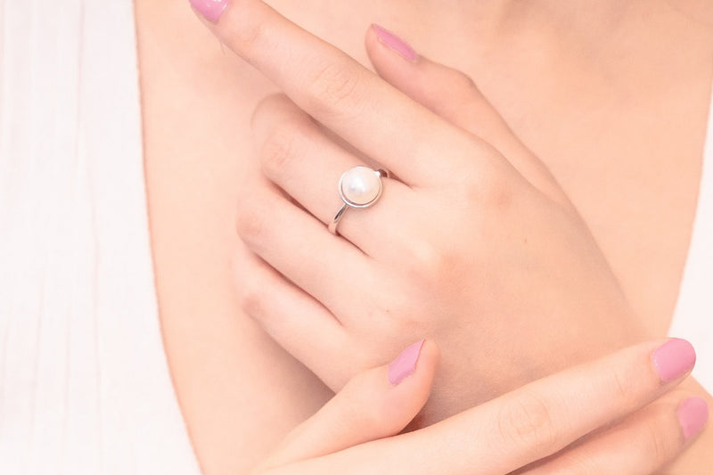 Close up of a womans hand wearing a silver and pearl ring