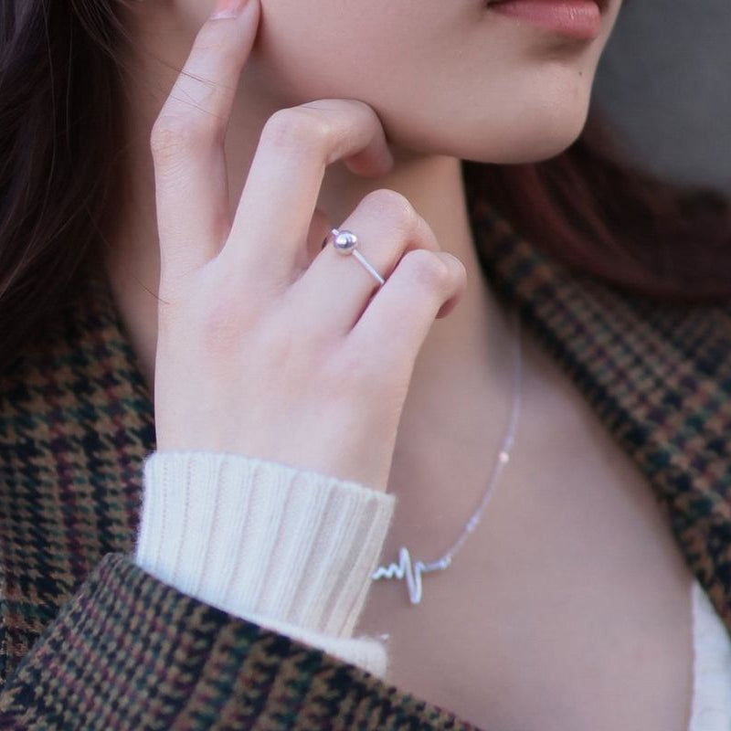 A model wearing a silver ring featuring a ball centerpiece