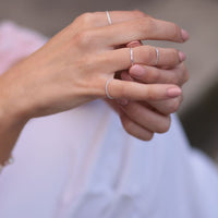 Close up of a womans hands wearing multiple silver rings featuring a weave design.