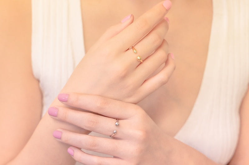 close up of a mdel wearing one gold and one silver sinple elegant design ring