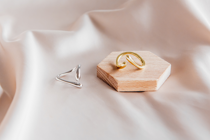 A polished gold ring and a polished silver ring with a simple elegant design, displayed on a white fabric background.