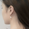 A pair of dangle pearl hook earrings in silver, worn by a woman model