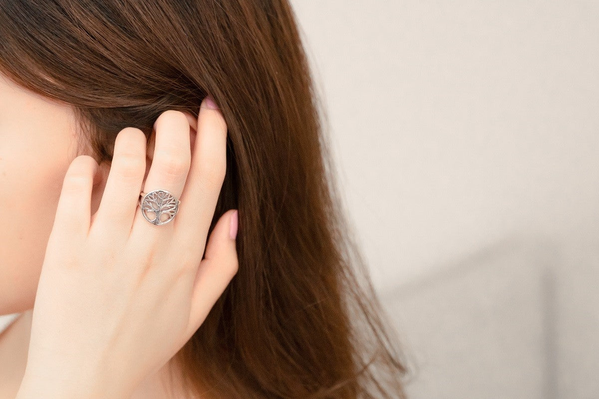 Close up of a model wearing a silver ring with a tree of life design