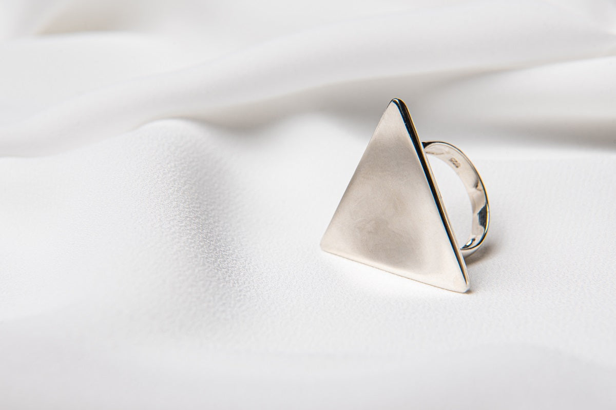 A silver ring with a triangular shape on a white background.