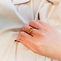 A close up of a model wearing a open design heard shaped gold vermeil ring
