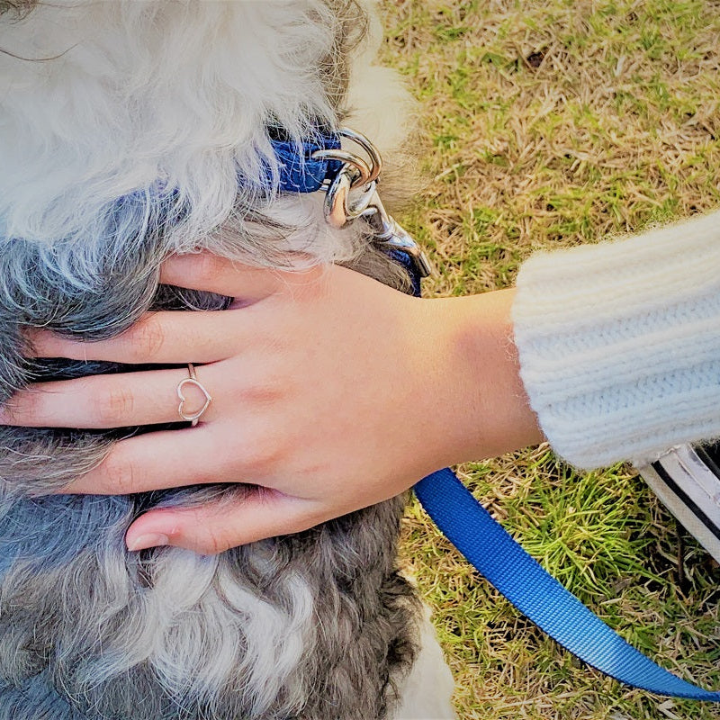 A close up of a model wearing a open design heard shaped silver ring