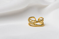 An adjustable gold vermeil ring with a twisted design, displayed on a white fabric surface.