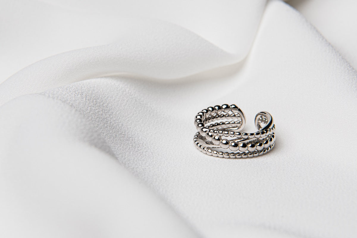 An adjustable sterling silver ring with a twisted design, displayed on a white fabric surface.