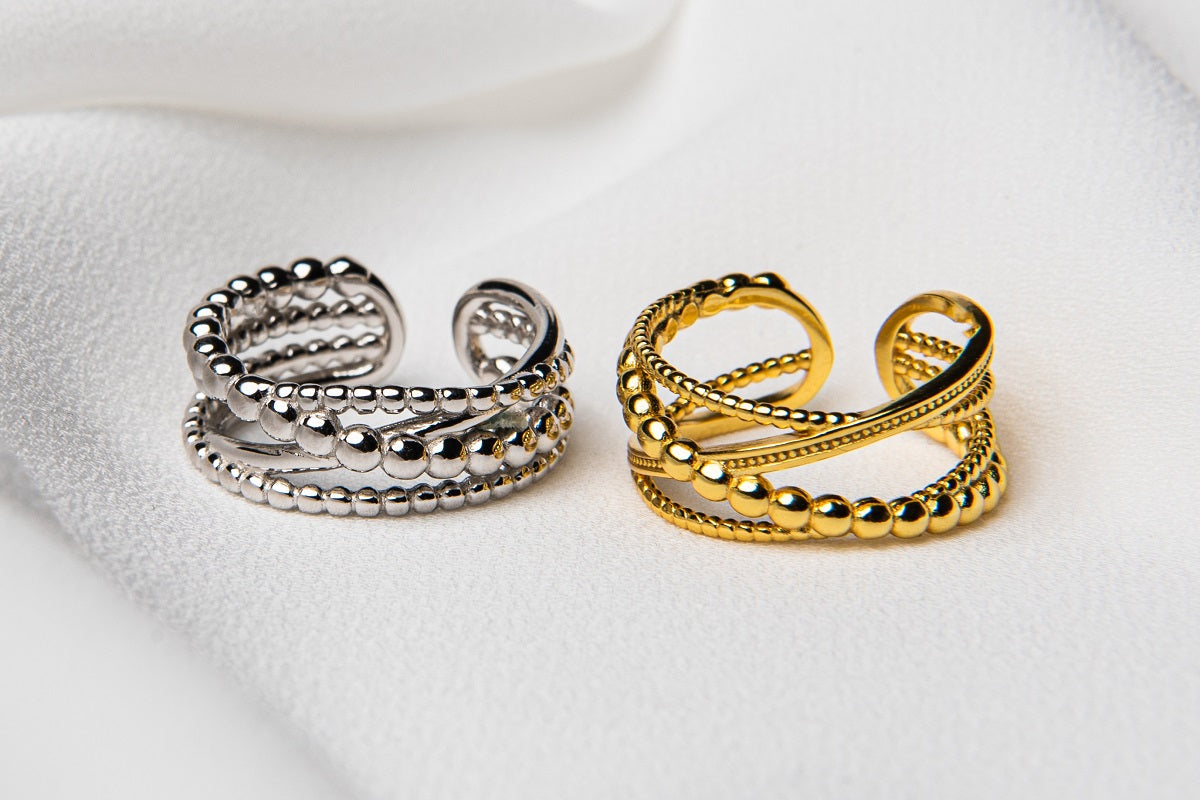 A silver and a gold adjustable ring on a white cloth