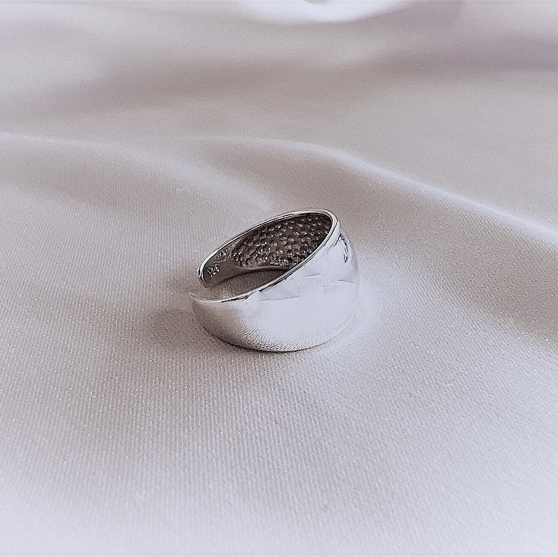 A plain silver toe ring on a white fabric surface.
