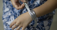 Close up of a woman wearing a multi stranded silver bracelet.