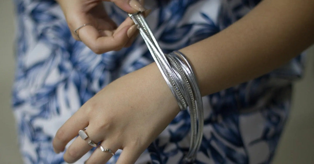 Close up of a woman wearing a multi stranded silver bracelet.