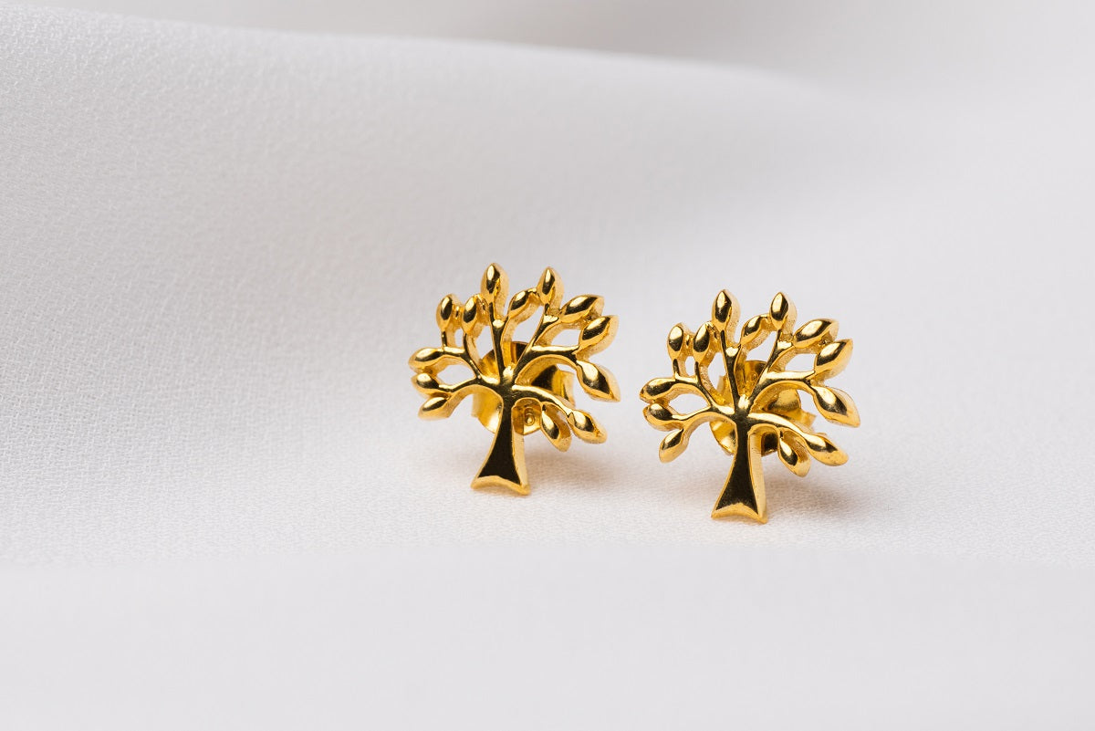 Gold tree shaped stud earrings on a white background