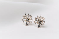 Silver tree shaped stud earrings on a white background