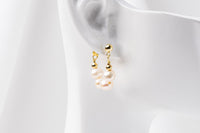 A pair of semi-dangle pearl earrings, made of sterling silver 925 and white color mini baroque-shaped pearls. On a white mannequine.