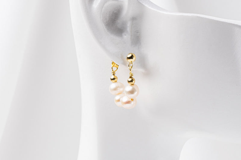 A pair of semi-dangle pearl earrings, made of sterling silver 925 and white color mini baroque-shaped pearls. On a white mannequine.