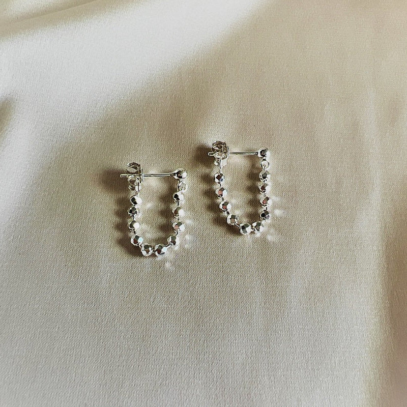 you and me silver earrings on a beige background 